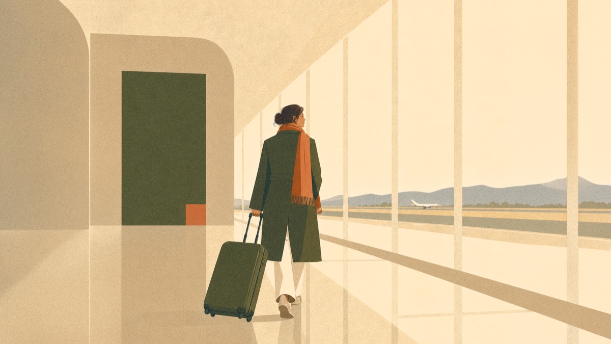 A traveler with a suitcase walking through a softly lit airport corridor, viewed from behind.